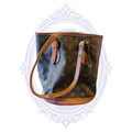 Front view of vintage 2001 Louis Vuitton Petit Bucket PM in monogram canvas with aged vachetta leather trim and shoulder straps.