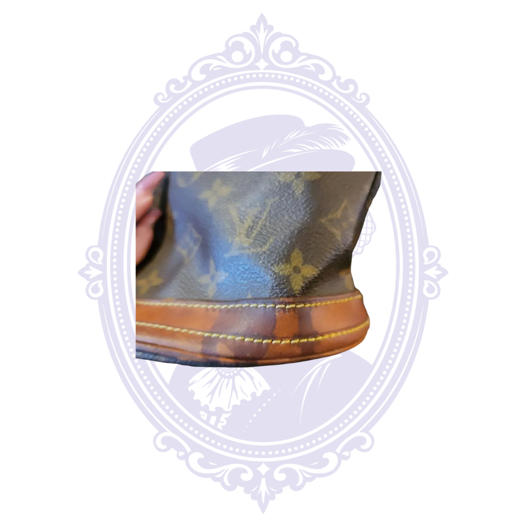 Close-up of vachetta leather base trim showing patina and wear on vintage Louis Vuitton Petit Bucket PM.