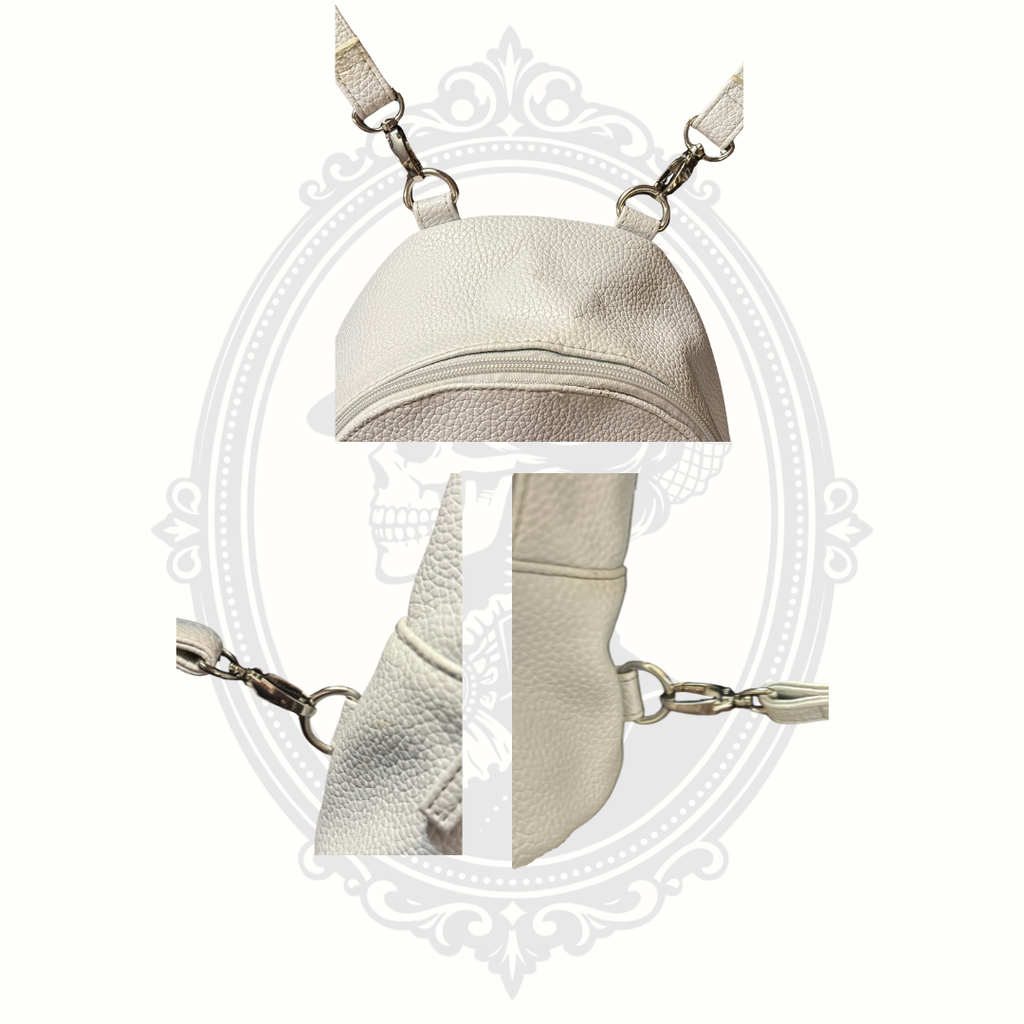 Close-up of detachable strap clasps on white mini backpack showing removable hardware