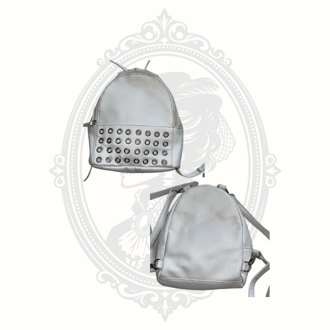 Close-up of silver grommet detailing on front pocket of white mini backpack