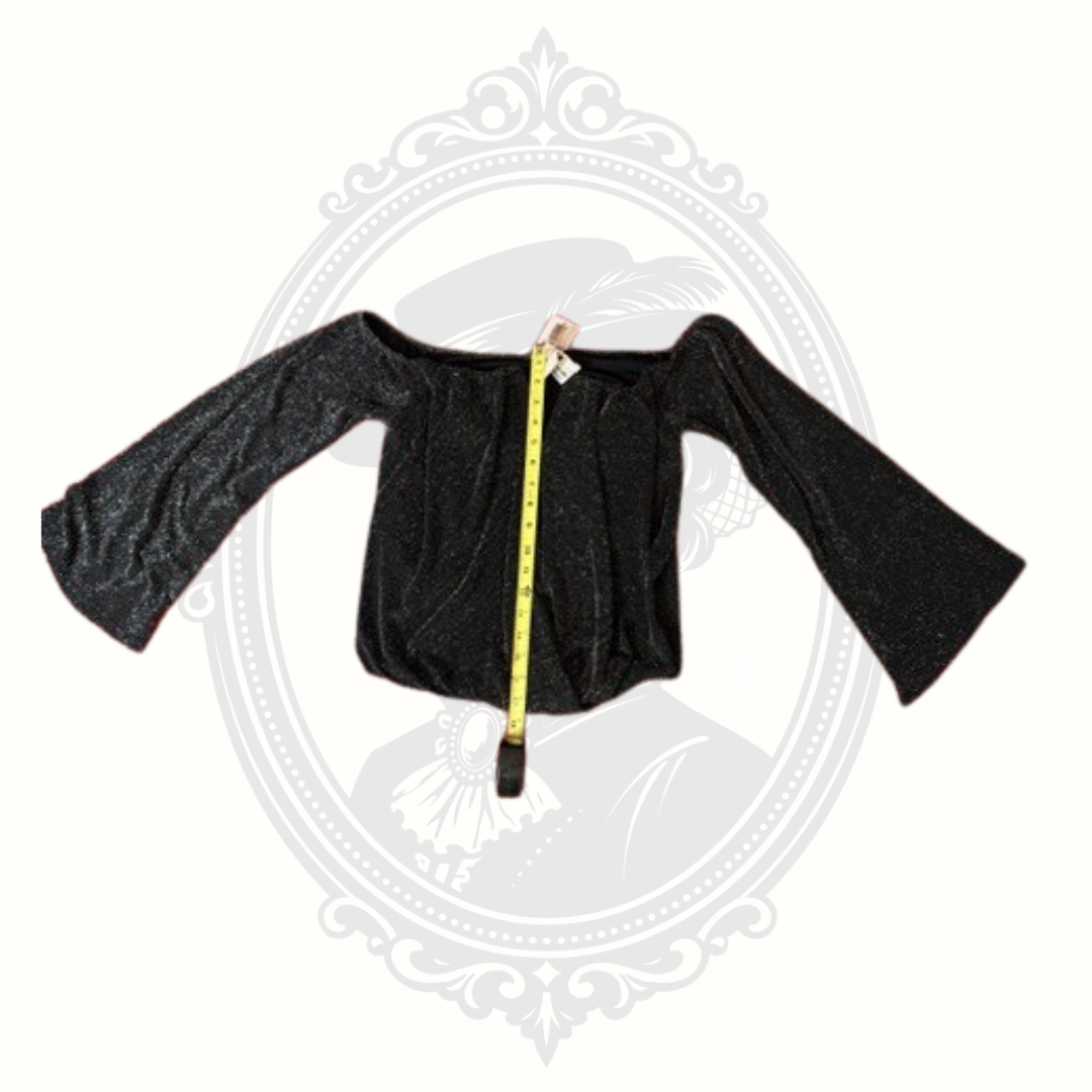 Black long-sleeve top with a measuring tape draped over it on a white background