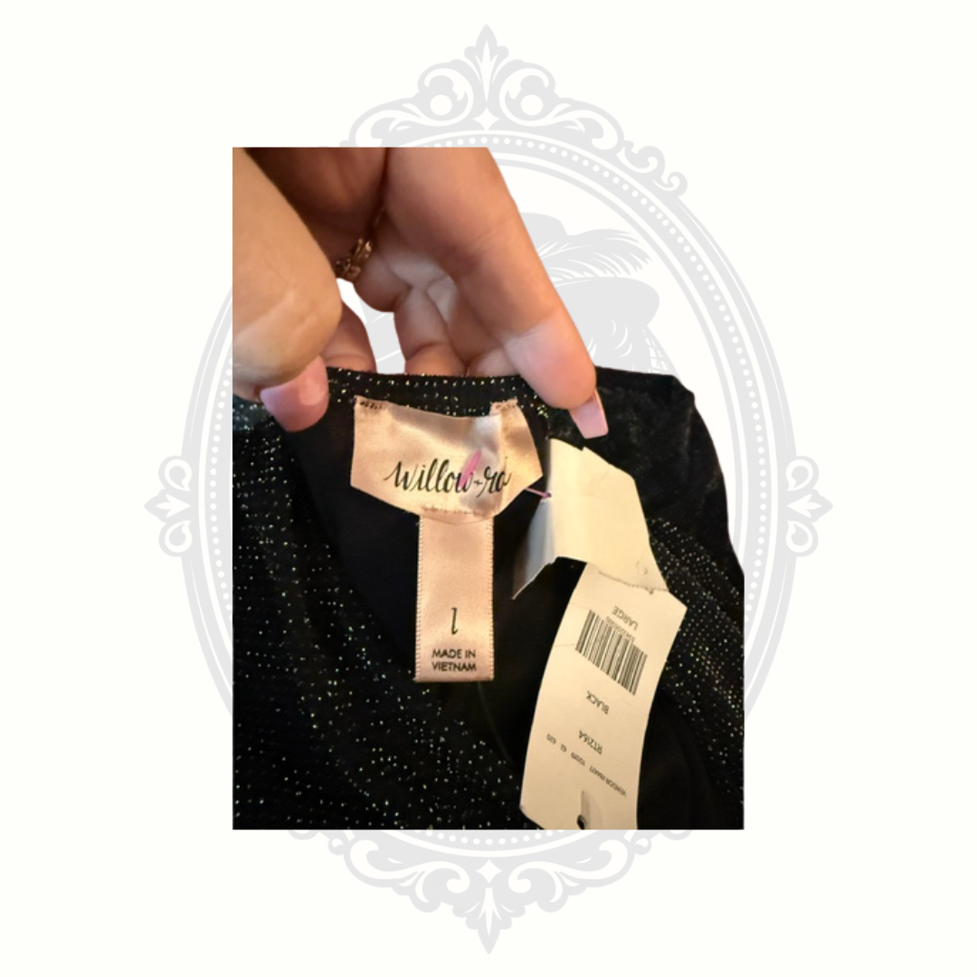 Black glittery garment with a visible tag, held by a hand against a white background.
